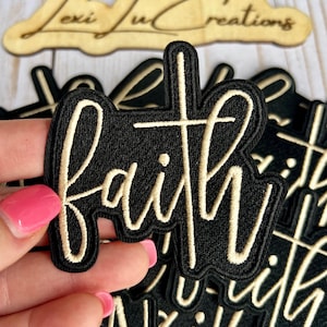 以下が含まれることがあります： 黒色の刺繍パッチ。筆記体で「faith」の文字が書かれており、デザインには十字架が組み込まれています。パッチはクリーム色の縁取りと文字で構成されています。同様のパッチも複数表示されています。