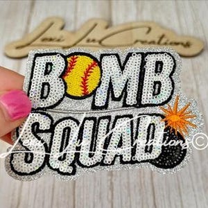 May include: A silver glitter patch with the words "BOMB SQUAD" in large, outlined letters. A yellow softball with red stitching replaces the "O" in "BOMB". An orange explosion and a black bomb are also featured.