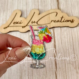 May include: A sequined embroidered patch shaped like a tropical cocktail glass. The drink features layers of pink, yellow, and teal sequins, topped with a yellow pineapple slice, a red hibiscus flower, a colorful paper umbrella, and a pink straw.