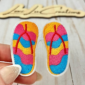 May include: Embroidered patch featuring a pair of colorful flip-flops. The flip-flops have a wavy design in pink, yellow, and blue, with red straps. The patch is white with a yellow border.