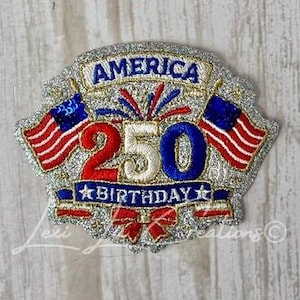 May include: A patriotic patch with the text "AMERICA 250 BIRTHDAY" in red, white, and blue. The design includes two American flags and a glittery silver border. The patch is likely for a celebration.
