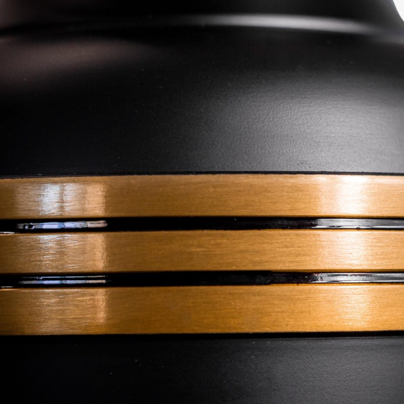 May include: A black object with three gold bands around the edge. The bands have a brushed metal finish.