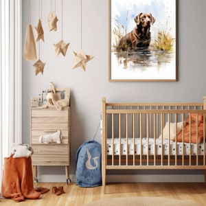 May include: A watercolor painting of a brown Labrador Retriever standing in a body of water with tall grass on either side. The painting is framed in a light wood frame and hanging on a white wall.