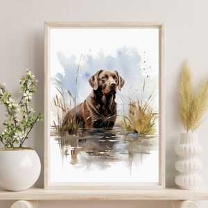 May include: Watercolor painting of a chocolate brown Labrador Retriever standing in a body of water with tall grass and reeds surrounding it. The dog is looking to the right of the image.