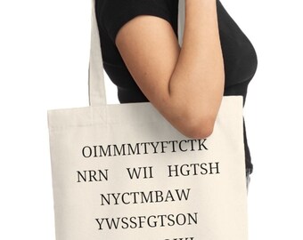 Puede incluir: Una bolsa de tela blanca con texto negro que dice "OIMMMTYFTCTK NRN WII HGTSH NYCTMBAW YWSSFGTSON HITHTGOIKI NMNH YOAR!"