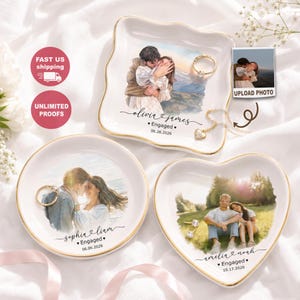 May include: Three ceramic trinket dishes with gold-trimmed edges, featuring custom printed photographs of couples, names, the word Engaged, and dates. The dishes are square, round, and heart-shaped, displaying rings and a gold necklace on their surfaces.