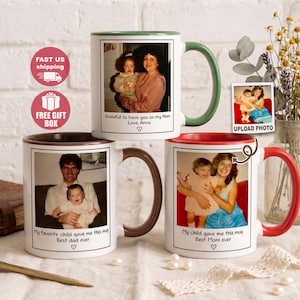 Könnte beinhalten: Weiße Keramikbecher mit individuellen Fotos und farbigen Griffen. Ein Becher hat einen grünen Griff, ein anderer einen braunen Griff und der dritte einen roten Griff. Jeder Becher zeigt ein Foto und Text: "Grateful to have you as my Mom", "My favorite child gave me this mug", und "My child gave me this mug".