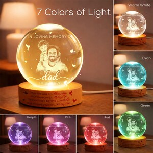 May include: A crystal ball night light with a photo of a father and child, illuminated in seven colors. The base is wooden, with the text "IN LOVING MEMORY OF dad 1965-2026". The text "Your life was a blessing..." is also visible.