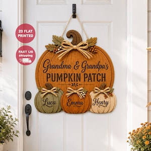 Könnte beinhalten: Ein hölzernes Türschild in Form eines großen orangefarbenen Kürbisses mit drei kleineren Kürbissen darunter. Der Text lautet Grandma & Grandpa's PUMPKIN PATCH, mit den Namen Luca, Emma und Henry auf den kleinen Kürbissen. Es hat eine Juteschnur zum Aufhängen, Stoffschleifen und künstliche Blätter.