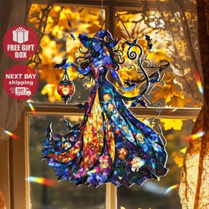 Könnte beinhalten: Eine Glasmalerei-Hexenfigur mit blauem Teint, die einen Hut trägt und eine Laterne hält. Das Kleid der Hexe ist ein Mosaik aus Farben, darunter Orange, Gelb und Blau, mit Totenkopf-Akzenten. Fledermäuse und dekorative Ranken umgeben die Figur.