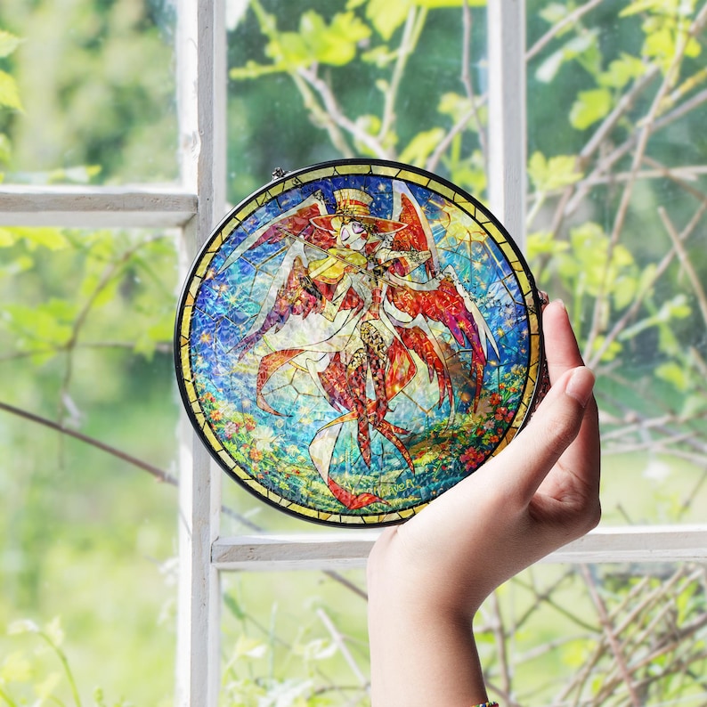 May include: A round stained glass art piece with a black metal frame. The artwork features a colorful illustration of a figure with wings, wearing a hat, and holding a violin. The background is a mix of blue, red, yellow, and green.