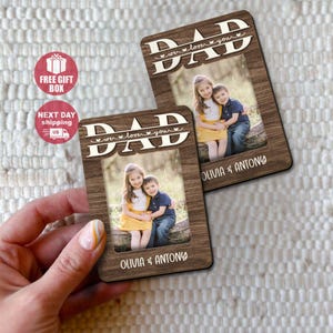 May include: Two wooden photo frames with the word "DAD" and the phrase "we love you" cut out at the top. Each frame holds a photo of a girl and a boy. The names "OLIVIA & ANTONY" are printed at the bottom of each frame.
