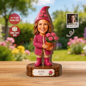 Könnte beinhalten: Eine skurrile Gartenzwergfigur mit einer lächelnden Frau, die einen rosa Pullover, Stiefel und einen mit Rosen geschmückten Hut trägt. Der Zwerg hält einen Topf mit rosa Rosen. Die Basis ist mit "JUNE Rose" graviert.