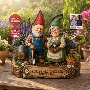 Könnte beinhalten: Eine flache 2D-Gartenzwerg-Paarfigur mit einem Mann in roter Mütze und blauer Latzhose sowie einer Frau in grüner Mütze und Schürze. Der Sockel trägt den Text GROWING OLD TOGETHER SINCE 1974, eine Metallgießkanne und einen Korb mit Gemüse.