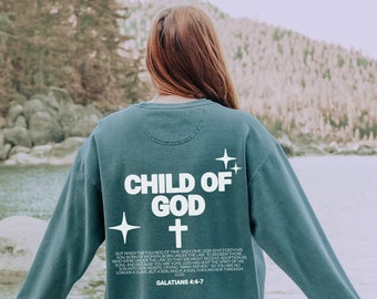 May include: A teal blue sweatshirt with the text "CHILD OF GOD" and a cross printed on the back. The text "GALATIANS 4:4-7" is printed below the cross.