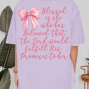 May include: A lavender t-shirt with a pink bow and the text "Blessed is she who has Believed that the Lord would fulfill His Promises to her".