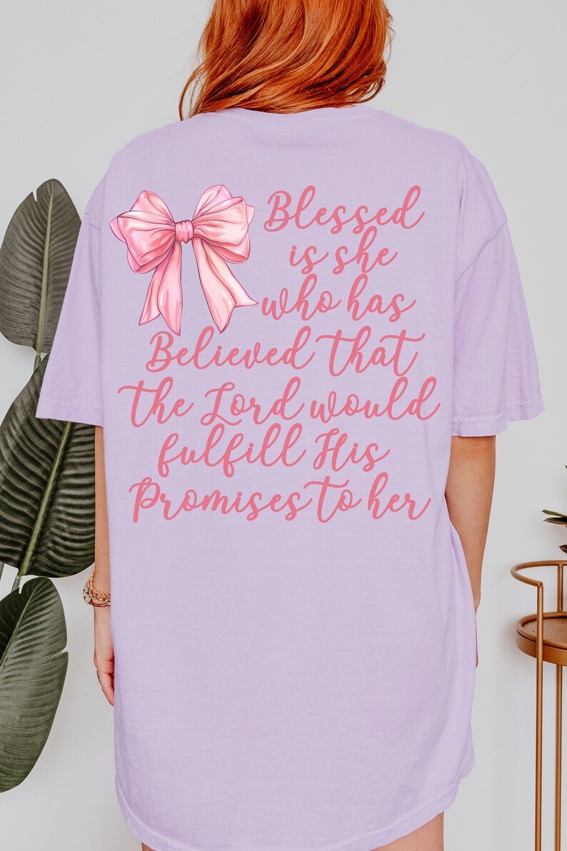 May include: A lavender t-shirt with a pink bow and the text "Blessed is she who has Believed that the Lord would fulfill His Promises to her".