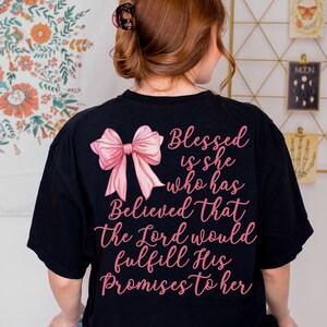 May include: Black t-shirt with a pink bow and the text "Blessed is she who has Believed that the Lord would fulfill His Promises to her" printed on the back.