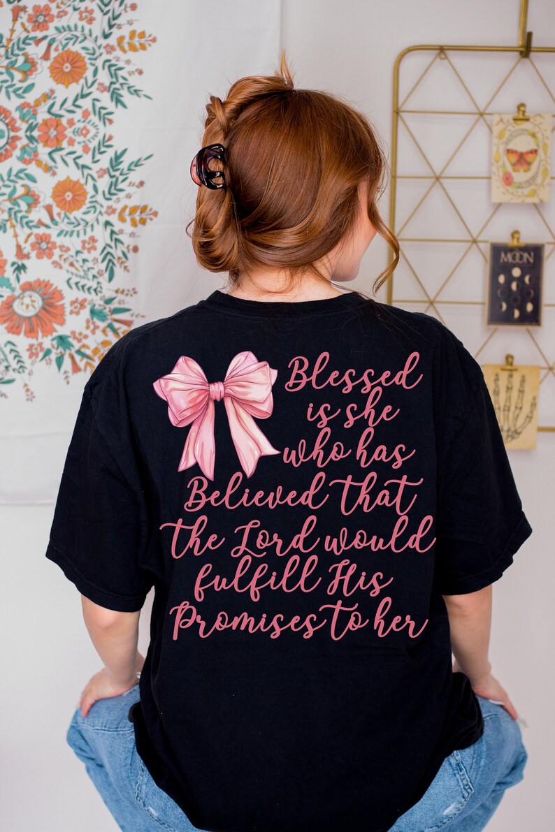 May include: Black t-shirt with a pink bow and the text "Blessed is she who has Believed that the Lord would fulfill His Promises to her" printed on the back.