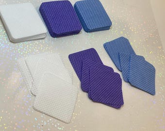 May include: A set of three different colored makeup remover pads. The pads are square and have a textured surface. There are white, light blue, and purple pads.