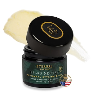 May include: A black jar with a gold lid and a green label that reads "Eternal Garden Beard Nectar Artisanal Styling Balm Style Hydrate Nourish Net Wt 45g | 1.6 oz Made in California". The jar is open and a small amount of white balm is visible on the lid.