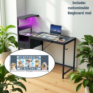 May include: A black computer desk with a keyboard mat featuring puppies and the text "ARE YOU TYPING THE DOGS ARE". The mat measures 31.5 inches long and 11.8 inches wide. Includes a customizable keyboard mat.