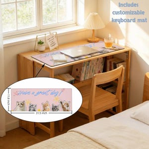 May include: A pink keyboard mat with the text "Have a great day!" and illustrations of five cats. The mat is 31.5 inches long and 11.8 inches wide. The mat is on a wooden desk with a laptop and other items.