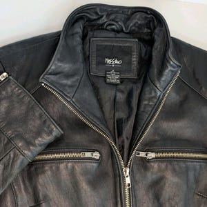 May include: Black leather jacket with a notched collar, two zippered pockets, and a full-length zipper closure. The jacket has a label that reads "Mossimo". The jacket is a size M.