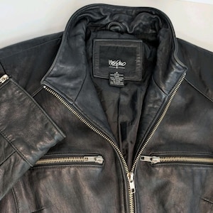 May include: Black leather jacket with a notched collar, two zippered pockets, and a full-length zipper closure. The jacket features a label that reads "Mossimo". The sleeves have zippered cuffs.