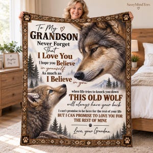 May include: A rectangular fleece blanket featuring a large wolf and a wolf pup, a mountain forest landscape, and the printed text: To My Grandson Never Forget That I Love You I hope you Believe in yourself As much as I Believe in you when life tries to knock you down THIS OLD WOLF will always have your back I can't promise to be here for the rest of your life BUT I CAN PROMISE TO LOVE YOU FOR THE REST OF MINE Love, your Grandma.