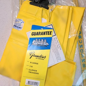 May include: Bright yellow Grund&eacute;ns Clipper Trousers, size X-Large, with black suspenders, in a clear plastic bag. The trousers have a guarantee tag and a Grund&eacute;ns of Sweden label. The label also states the trousers are made in Portugal.