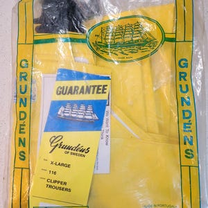 May include: Yellow Grund&eacute;ns Clipper Trousers, size X-Large, in a clear plastic bag. The package includes a guarantee card and a yellow tag with product information. The trousers are labeled as medium duty.
