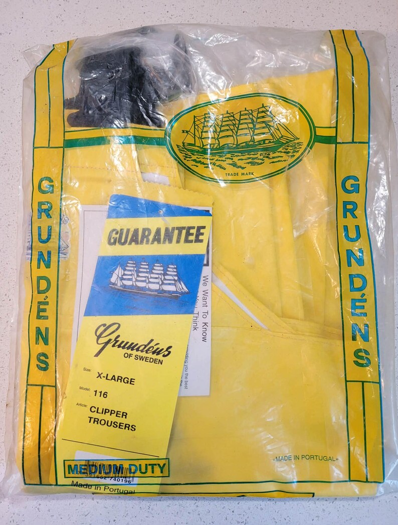 May include: Yellow Grund&eacute;ns Clipper Trousers, size X-Large, in a clear plastic bag. The package includes a guarantee card and a yellow tag with product information. The trousers are labeled as medium duty.