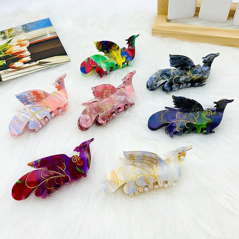 Peut inclure: Ensemble de six pinces &agrave; cheveux color&eacute;es en forme d'oiseau avec des ailes. Les pinces sont en plastique et ont une finition brillante. Les couleurs incluent le rose, le bleu, le vert, le violet, le blanc et le noir.