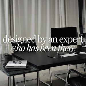 May include: A modern office space with a black desk, computer monitors, and a keyboard. The text "designed by an expert who has been there" is displayed in white. A glass cylinder and books are on a side table.