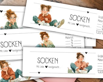 Op de afbeelding: Verschillende witte kaarten met het woord "SOCKEN" en de zin "Mit Liebe handgemacht" in het zwart gedrukt. Elke kaart bevat een illustratie van een jonge vrouw die aan het breien is. De kaarten bevatten ook ruimtes voor maat en materiaalpercentages.