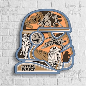Op de afbeelding: Een gelaagd papierkunstig ontwerp in blauw en bruin met personages en voertuigen uit het Star Wars-universum. Het ontwerp bevat Darth Vader, Luke Skywalker, een TIE-jager, een X-wing, R2-D2, Yoda en de Mandalorian. Het ontwerp is getiteld "Star Wars".
