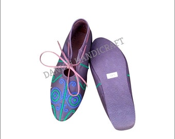 May include: A pair of purple leather shoes with green and blue embroidery. The shoes have laces and a pointed toe. The size 10.5 is written on the sole of one shoe.