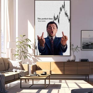May include: A framed print featuring a man in a suit, gesturing with both hands. The background shows a stock market graph. Text on the print reads "The perfect time Never comes."