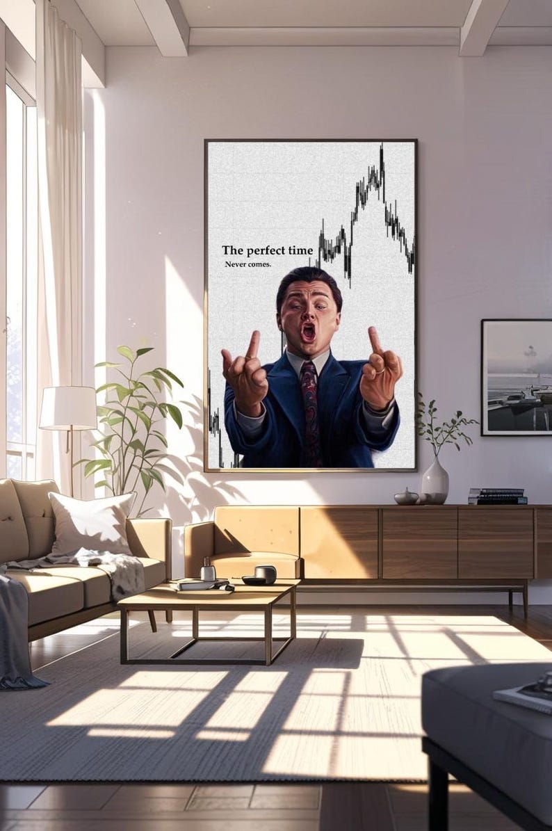 May include: A framed print featuring a man in a suit, gesturing with both hands. The background shows a stock market graph. Text on the print reads "The perfect time Never comes."