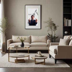 May include: A framed print featuring a man in a suit gesturing with both middle fingers up, set against a stock chart background. The text "The perfect time" is displayed on the print. The print hangs above a beige sofa in a living room.