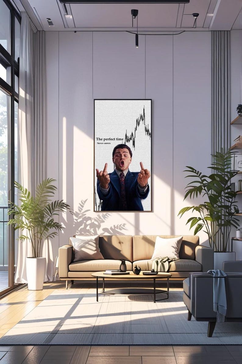 May include: A framed print featuring a man in a suit gesturing with both middle fingers up, with the text "The perfect time" and a stock chart. The print hangs on a white wall in a modern living room setting.