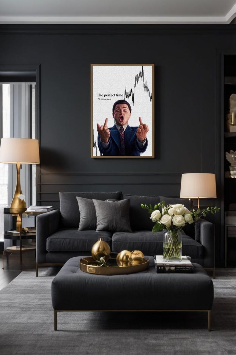 May include: A framed print featuring a man in a suit gesturing with both hands, with the text "The perfect time. Never comes." The print hangs above a dark gray sofa with gray pillows and a matching ottoman. A gold tray holds decorative spheres.