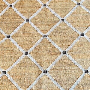 May include: A beige woven rug with a white diamond pattern and black accents.