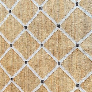 May include: A beige rug with a white diamond pattern and black accents. The rug is woven with a textured, natural fiber.
