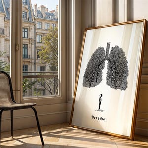 May include: A framed art print featuring a black and white illustration of lungs resembling trees, with a small figure below. The print is leaning against a wall, with the word "Breathe" at the bottom. A chair sits near a window.