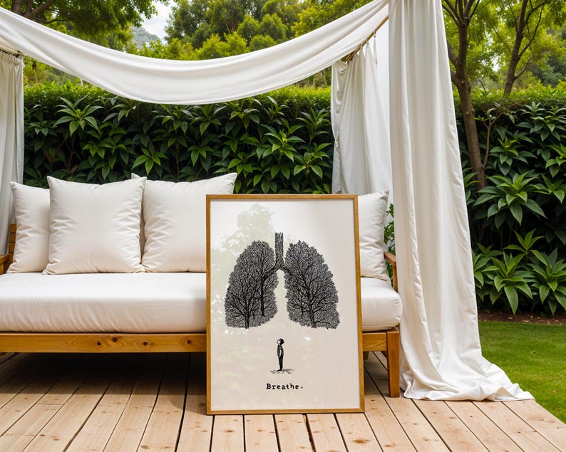 May include: A framed art print featuring a black and white illustration of lungs shaped like trees. A small figure stands below the lungs. The word "Breathe" is printed at the bottom. The artwork is displayed outdoors.