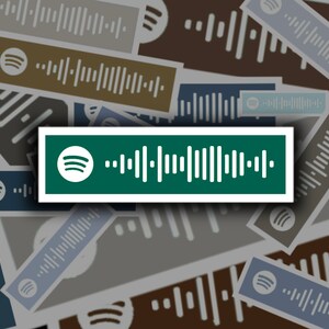 Op de afbeelding: Een groene rechthoekige sticker met een wit Spotify-logo en een zwart-witte barcode. De sticker is omringd door andere vergelijkbare stickers in verschillende kleuren.