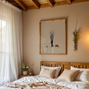 Puede incluir: Interior de dormitorio con una cama de madera, ropa de cama blanca y almohadas beige. Una obra de arte enmarcada cuelga sobre la cama, y cortinas blancas transparentes enmarcan una ventana. Una l&aacute;mpara colgante y un peque&ntilde;o jarr&oacute;n de flores completan la decoraci&oacute;n.