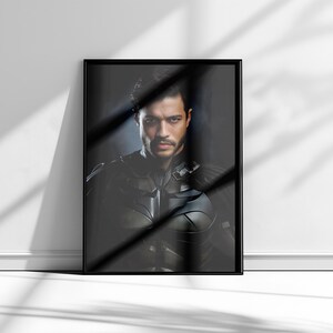 May include: A framed black and white portrait of a man with dark hair and a serious expression. He is wearing a dark suit and tie. The background is a dark, blurry image.
